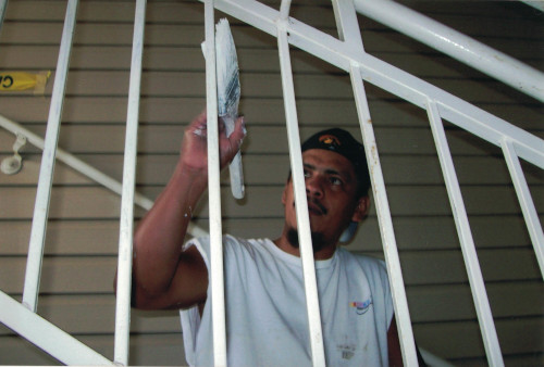 Photo of carefully painting the railing along some stairs.