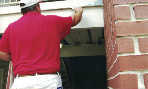 Photo of Scott painting the primed metal surface by brush.